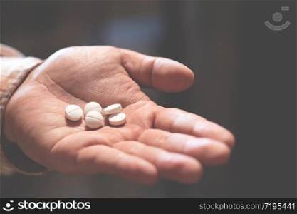 close up hand man holding taking multiple pills. Stop drug use Taking Medication health care medical concept. narcotic sleeping pills dark background.