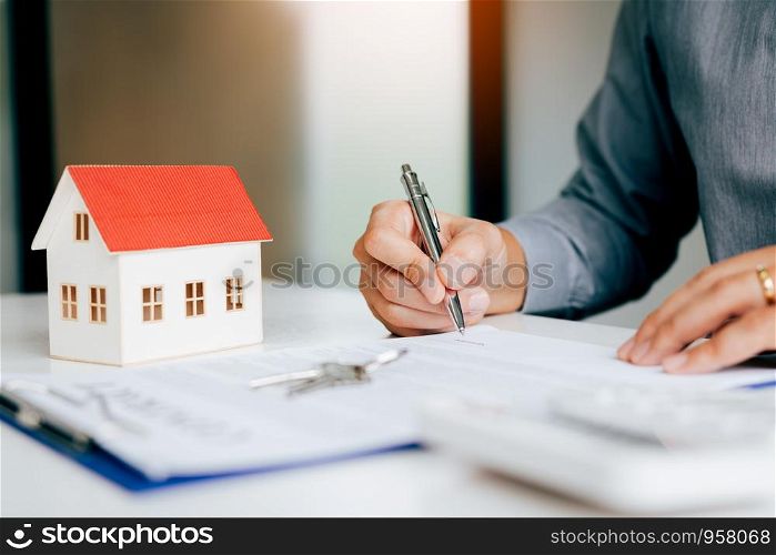 Close up hand man signing paper contract agreement for buying house.