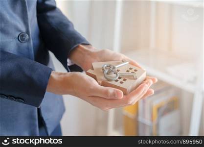 Close-up hand of Asian business woman are holding key and model houses in the office