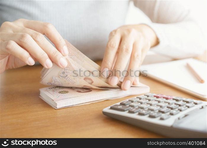 Close-up hand of asian woman using calculator counting and count money in home.