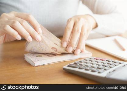 Close-up hand of asian woman using calculator counting and count money in home.