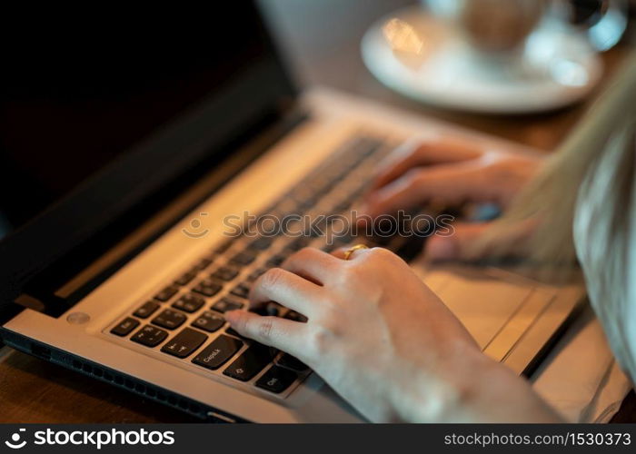 Close up hand of business woman working with laptop in coffee shop cafe,Warm tone,Selective focus