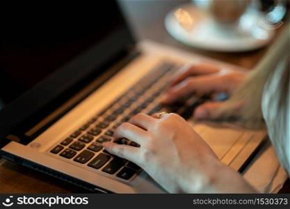 Close up hand of business woman working with laptop in coffee shop cafe,Warm tone,Selective focus