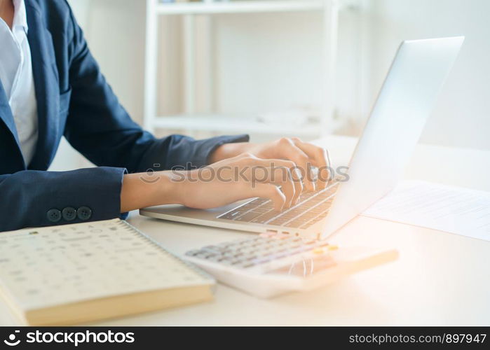 Close-up hand of businesswoman using a laptop working at the office in morning light