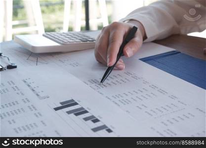 close-up hand of people working in office, studying using calculator and writing something with documents and chart on table. business and accounting concept