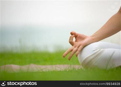 Close up hand of woman practice yoga meditation lotus pose on green grass on the beach in thailand,Feeling so comfortable and relax in holiday ,Healthy Concept