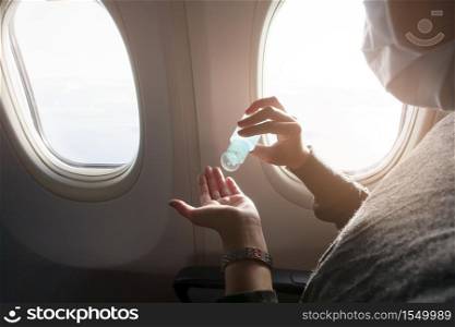 Close up hand of woman with protective mask is using alcohol gel onboard, covid-19 protection, new normal travel concept . . Close up hand of woman with protective mask is using alcohol gel onboard, covid-19 protection, new normal travel concept
