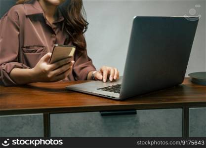 Close up, Hand of Young asian woman holding smartphone and use laptop computer, New normal she Stay at home and works from home during self-isolation and quarantine covid-19 coronavirus outbreak