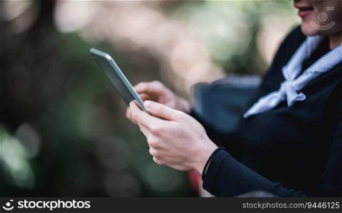 Close up  hand of Young pretty woman sitting in chair and use tablet with happy while c&ing in nature park, copy space