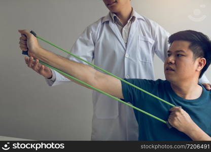 Close up hand patient doing stretching exercise with a flexible exercise band and a physical therapist hand to help in clinic room.