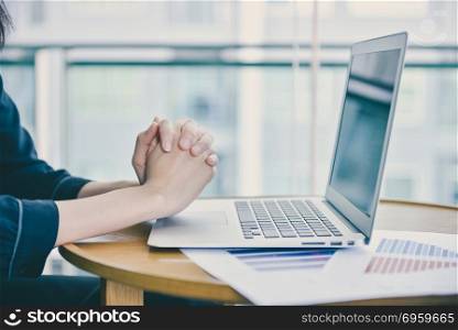 Close up hand praying for victims in front of a laptop