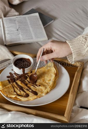 close up hand spreading chocolate pancake