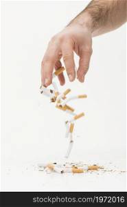 close up hand throwing broken cigarettes against white background. High resolution photo. close up hand throwing broken cigarettes against white background. High quality photo