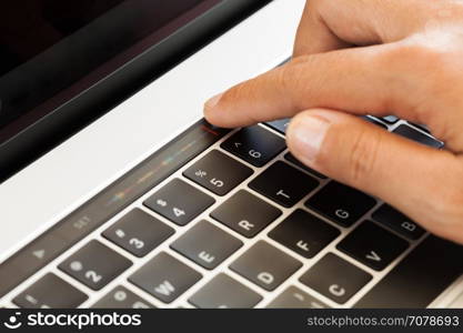 Close-up hand touching touch bar on laptop computer