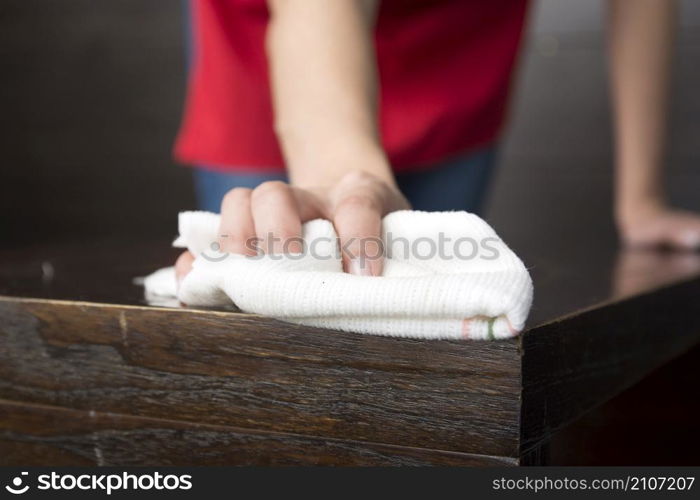 close up hand wiping wooden table with white napkin
