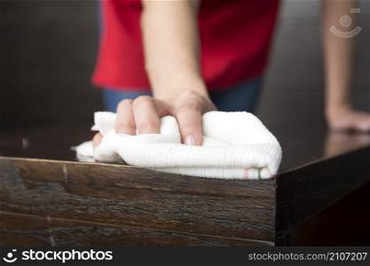close up hand wiping wooden table with white napkin