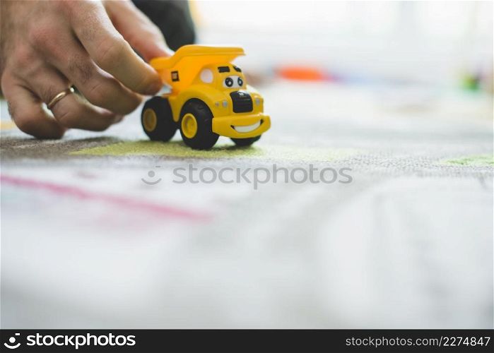 close up hand with yellow toy car