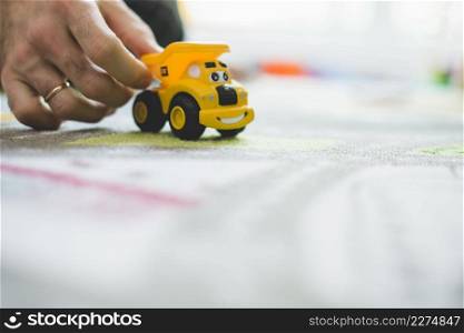 close up hand with yellow toy car
