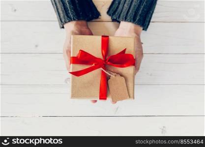 Close up hand woman holding and person gift box on wood table for New year background.
