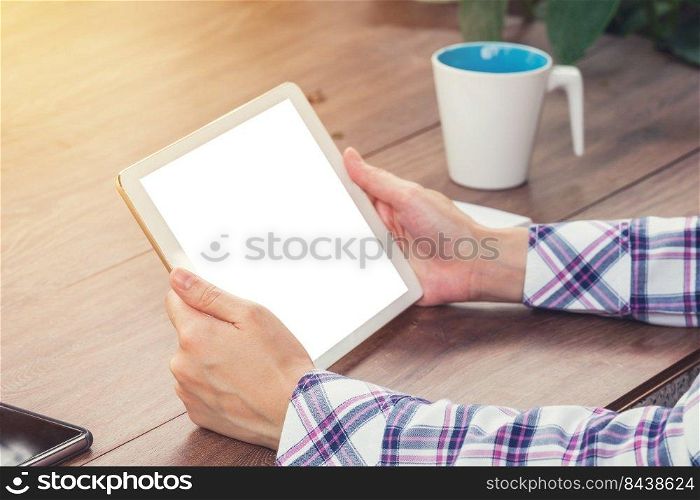 Close up hand woman holding tablet blank screen display on wood table with sunlight. Vintage toned.