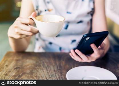 close up hand woman using smartphone in coffee shop with depth of field