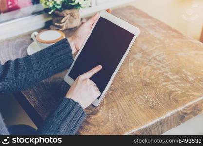 Close up hand woman using tablet in coffee shop with vintage tone.