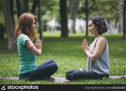 Close up hands. Happy girls doing yoga in the park on the grass. Healthy and Yoga Concept