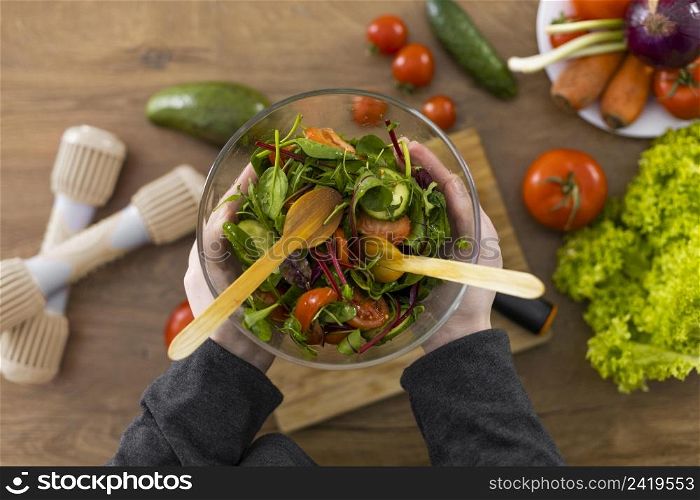 close up hands holding bowl with salad