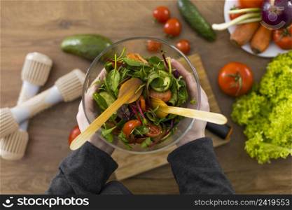 close up hands holding bowl with salad