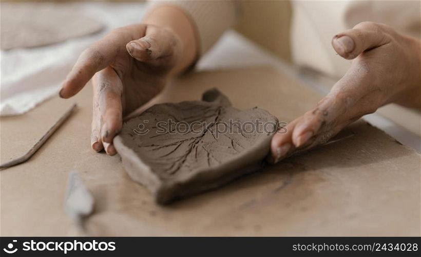 close up hands holding clay leaf