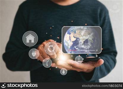 Close up hands holding smartphone. man using cellphone for watching video on internet about energy sources environmen. Renewable green energy eco saving technology and global warming concept.Elements of this image furnished by NASA