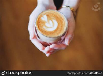 Close up hands of barista woman holding cup of hot cappuccino coffee in the cafe