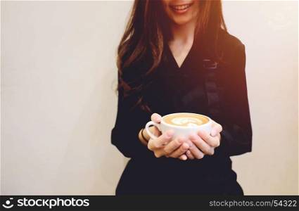 Close up hands of barista woman holding cup of hot cappuccino or latte coffee and smiling in the cafe, copy space