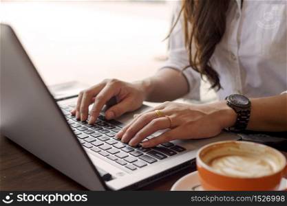 Close up hands of Business woman wearing white shirt working with laptop and coffee cup in coffee shop cafe,Business and Financial concept