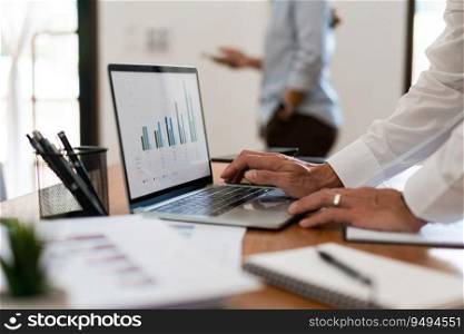 Close up hands of businessman is reading financial data and typing on laptop keyboard in office.