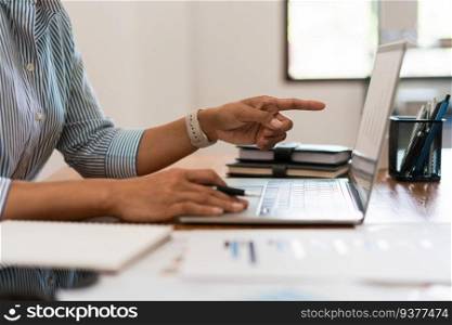 Close up hands of businesswoman is pointing on screen to reading data and typing on laptop keyboard.