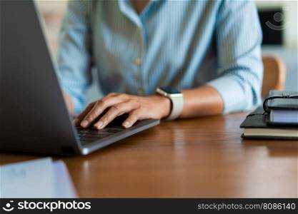 Close up hands of businesswoman typing data on laptop keyboard while working on the desk in office.