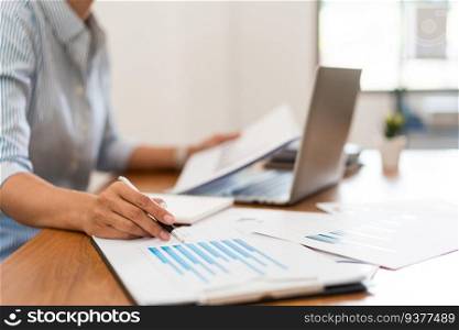 Close up hands of businesswoman working and reading financial document to writing notes in notebook.