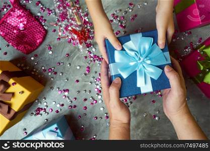 Close up hands of parent giving a gift with colorful gift box and little star craft background . Present gifts ,Christmas ,New year seasonal holiday give concept .Top view .