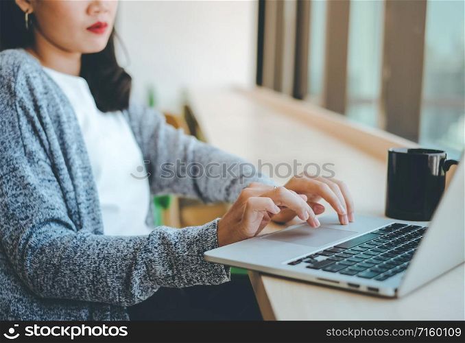 Close up hands of young businesswoman typing on computer laptop at the office or cafe, bsuiness concept