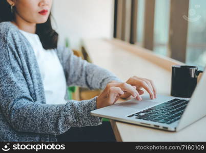 Close up hands of young businesswoman typing on computer laptop at the office or cafe, bsuiness concept