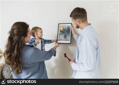 close up happy family holding picture frame against wall new home