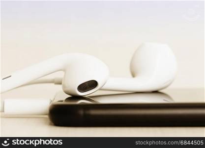 Close-up headphone stack on phone, modern phone's earbuds device accessories
