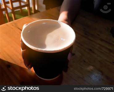 Close up hot coffee cup on wooden table in cafe with soft light morning