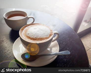 Close up hot coffee cup on wooden table in coffee shop with soft light morning