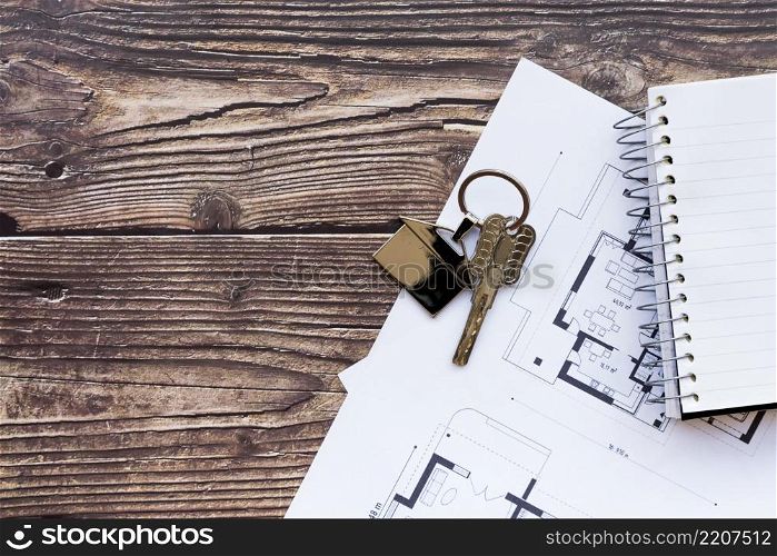 close up house keys blueprint new home spiral notebook wooden textured backdrop