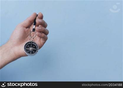 close up human hand holding navigational compass blue backdrop