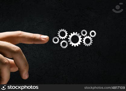 Close up human hand pointing at gears mechanism