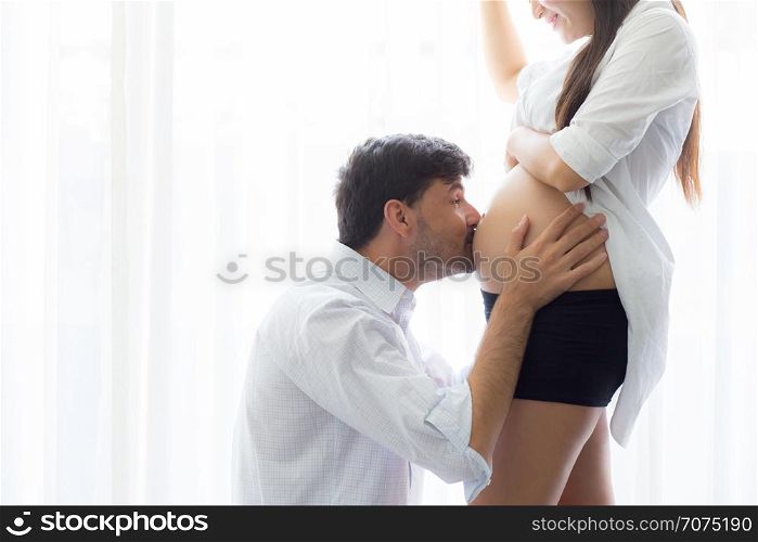 close up husband kiss pregnant woman belly - love of father to the unborn child.