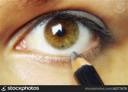 Close up image of an eye and putting eye liner on it.
